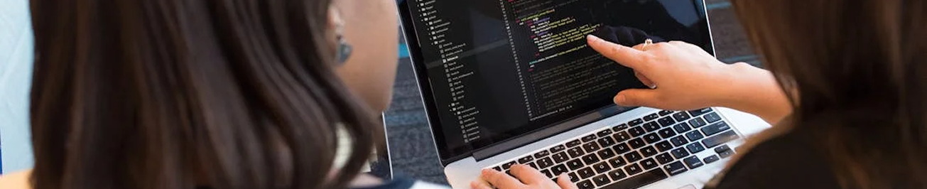 Estudiante programando en laptop con código en pantalla